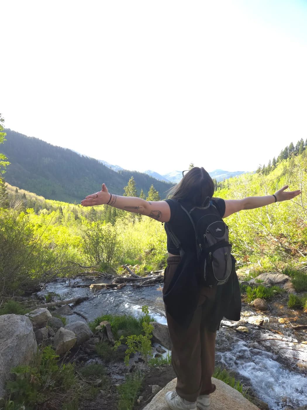 Syd at a mountain creek with her arms outstretched